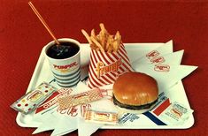 a tray that has some fries and a hamburger on it with ketchup in a cup