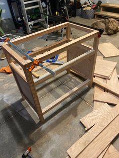 some tools are laying on the floor next to wood planks and plywood boards