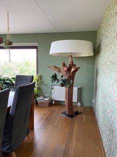 a wooden table sitting next to a lamp on top of a hard wood floor covered in plants