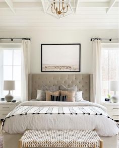 a bedroom with white walls and carpeted flooring has a large bed in the center