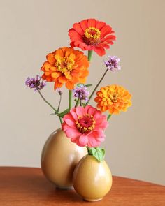 three vases with flowers in them sitting on a table