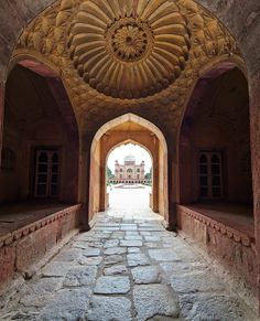 an archway leading into a building with stone floors and arches on both sides that lead to the main entrance