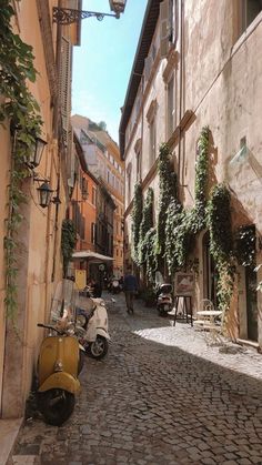 a scooter parked on the side of a cobblestone street next to buildings