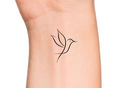 a small tattoo on the wrist of a woman's arm, with a bird