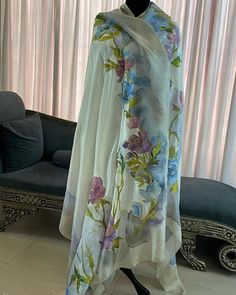 a dress on display in front of a window with curtains and a couch behind it