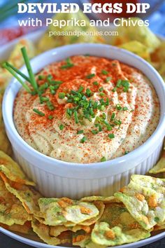 deviled eggs dip with paprika and chives in a white bowl surrounded by tortilla chips