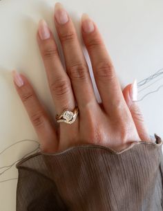 a woman's hand with a diamond ring on top of her left hand, resting against a white surface