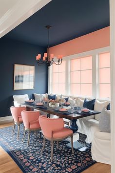 a dining room with blue walls, pink chairs and a rug in front of the table