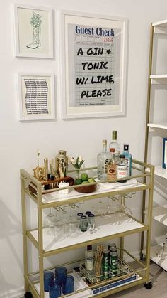 a bar cart with drinks on it in front of some pictures and other items hanging on the wall