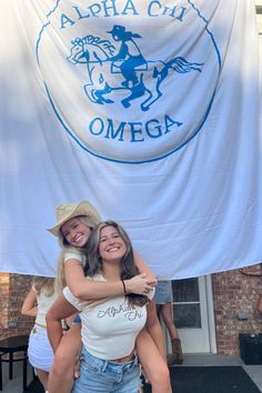 two women hugging each other in front of a banner