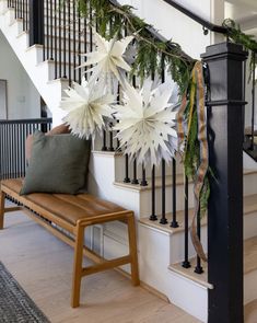 a wooden bench sitting under a stair case next to a banister with white flowers on it