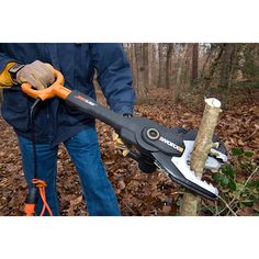 a man holding a chainsaw in the woods with leaves on the ground around him