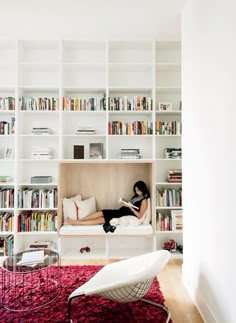 a woman laying on a couch in front of a bookshelf filled with books