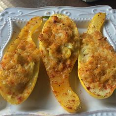 three stuffed squash on a white plate with some parmesan cheese and seasoning