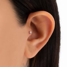 a woman wearing an ear piercing with a small diamond in the middle of her ear