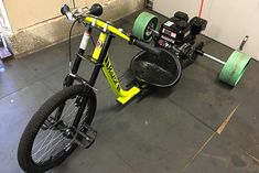 a bicycle is parked in a garage next to some green hoses on the floor