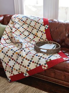 a brown leather couch with a quilt on it