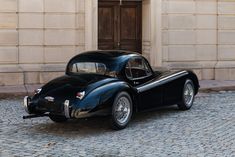 an old black car parked in front of a building