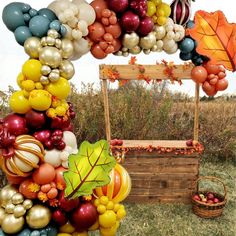 a bunch of balloons that are hanging from a wooden structure with a bench in the middle