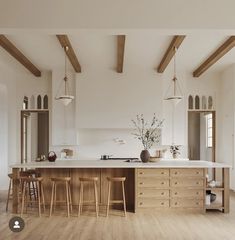 a large kitchen with wooden floors and white walls, along with two bar stools