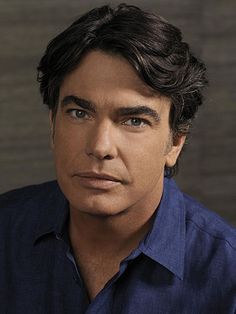 a close up of a person wearing a blue shirt and looking at the camera with a serious look on his face