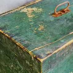 an old green suitcase sitting on top of a wooden table next to a white wall