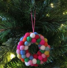 a christmas ornament hanging from a tree decorated with pom - poms