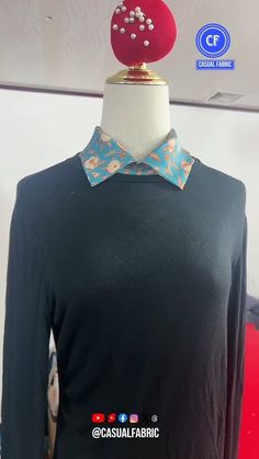 a mannequin wearing a black shirt with flowers on it and a red hat on top