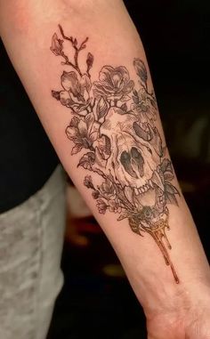 a person with a tattoo on their arm holding a flower and skull in the middle