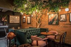 the interior of a restaurant with green couches and tables