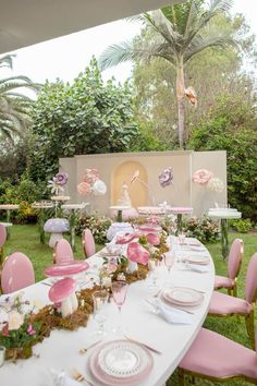 a long table with pink chairs and plates on it