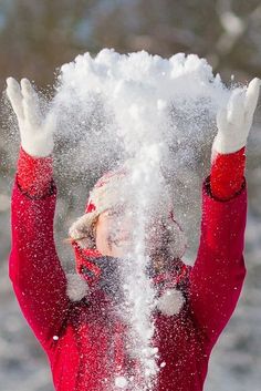 a person in a red jacket throwing snow into the air with their hands and arms