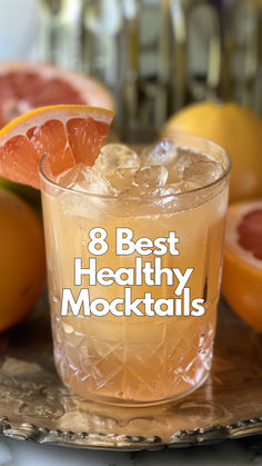 a close up of a drink on a tray with grapefruit and oranges in the background