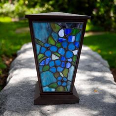 a stained glass vase sitting on top of a stone