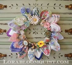 a wreath made out of cloths and flowers on top of a white dresser door