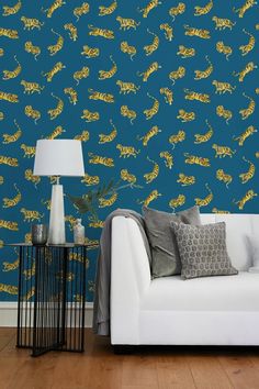 a couch sitting in front of a blue wall with yellow tigers on it