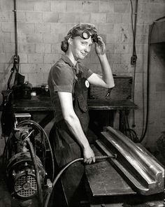 an old black and white photo of a woman working in a factory