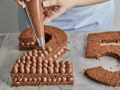 someone is decorating a cake with chocolate frosting