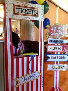 a carnival ticket booth with balloons and signs