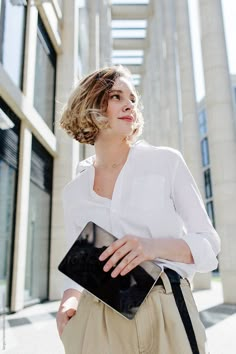 a woman is walking down the street with her hand on her hip while holding a black purse