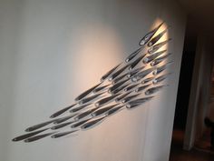 there is a sculpture made out of knives on the wall in front of a white wall