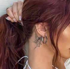 a woman with tattoos on her neck and behind her ear is looking at the camera