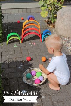 a baby sitting on the ground playing with some balls in front of an array of chairs