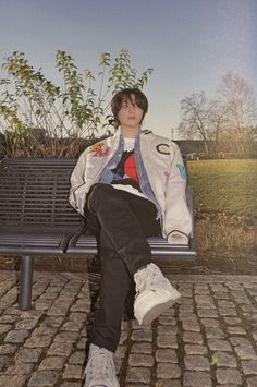 a young man sitting on top of a metal bench