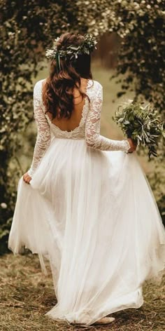 a woman in a white dress is walking through the woods with her back to the camera