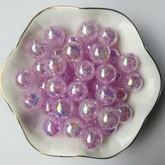 a white bowl filled with lots of shiny purple balls