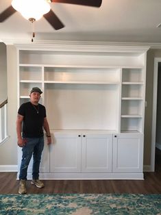 a man standing in front of a white bookcase