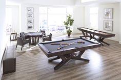 a pool table in the middle of a living room with chairs and tables around it