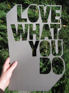 someone holding up a poster with the words love what you do on it in front of some trees