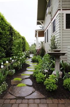 a stone path between two buildings leading to a garden